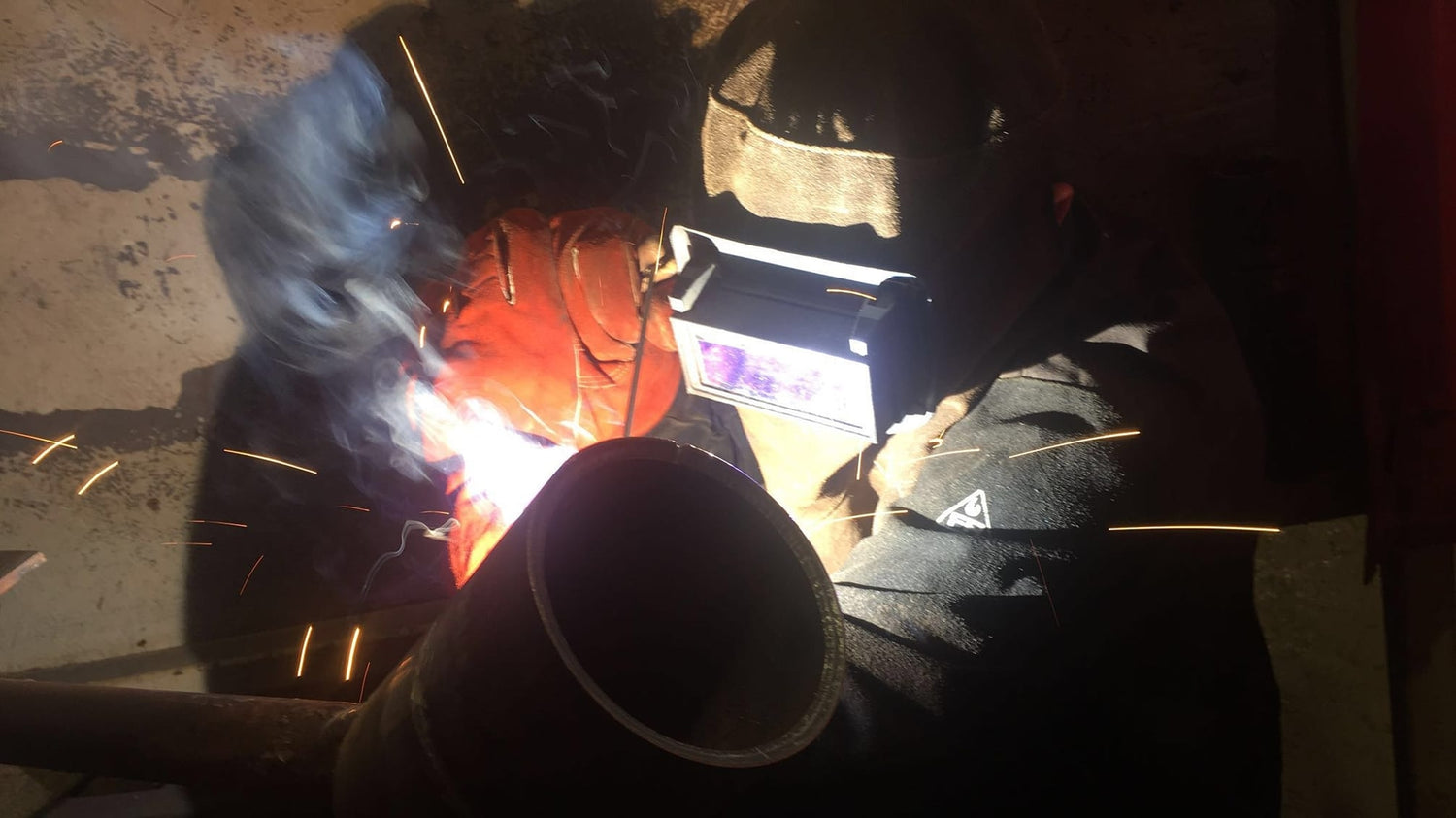 Person welding with sparks flying in a dark setting